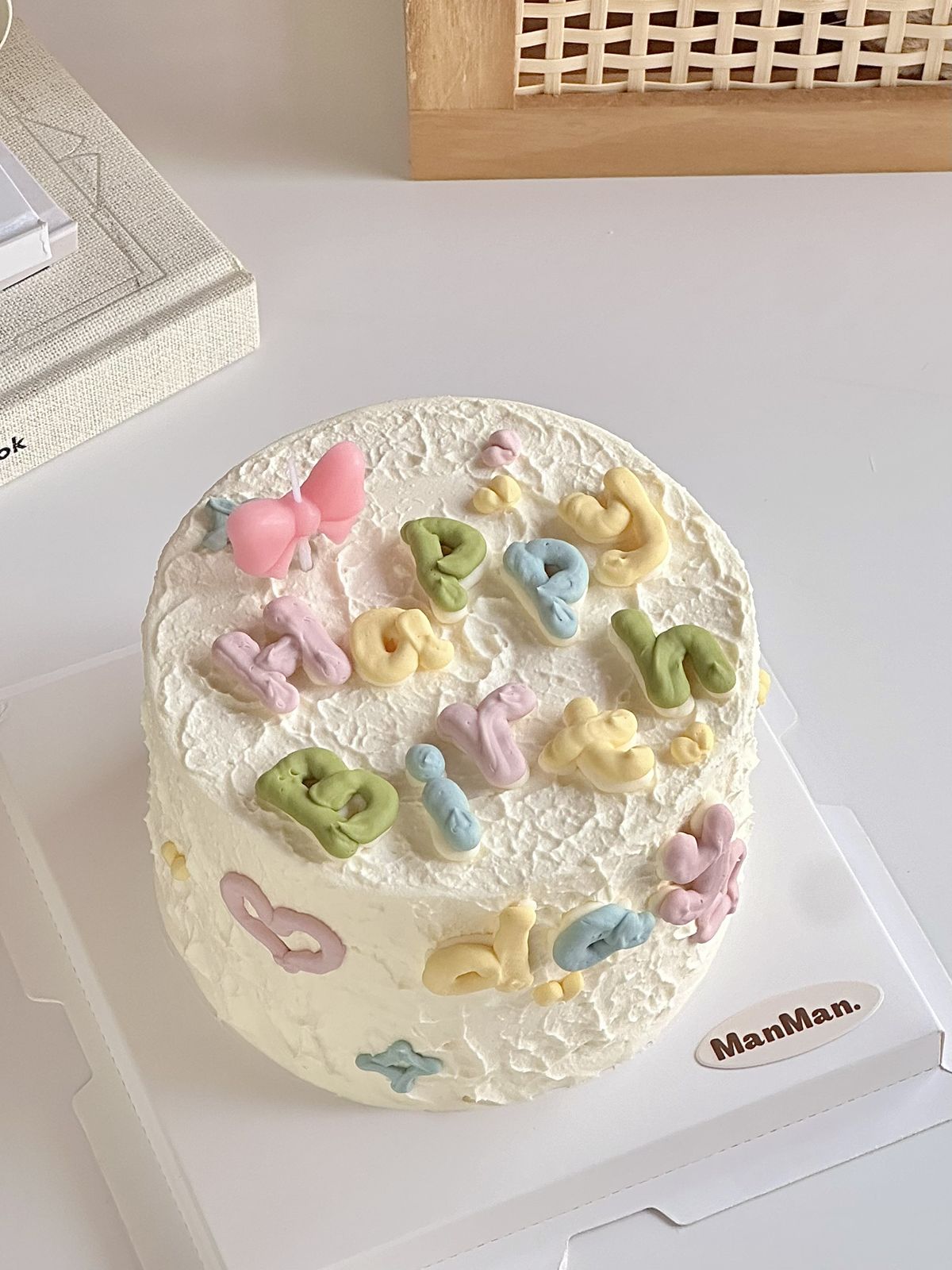 White Korean bento cake in a lunchbox featuring a minimalist line-art character holding a cake slice surrounded by colorful sprinkles and Korean birthday text.