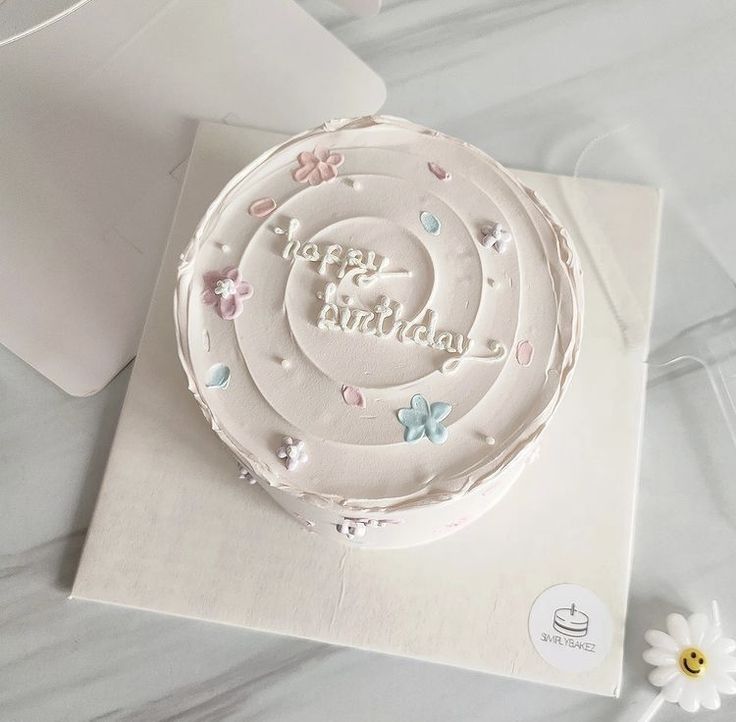Aesthetic lavender-toned bento cake featuring textured spiral frosting, pastel buttercream flowers, and elegant 'happy birthday' script.