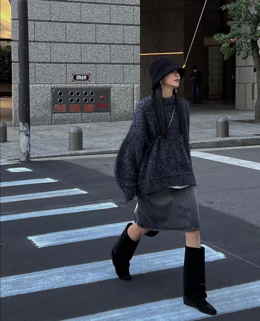 A chunky knit sweater paired with a denim skirt and knee-high black boots.