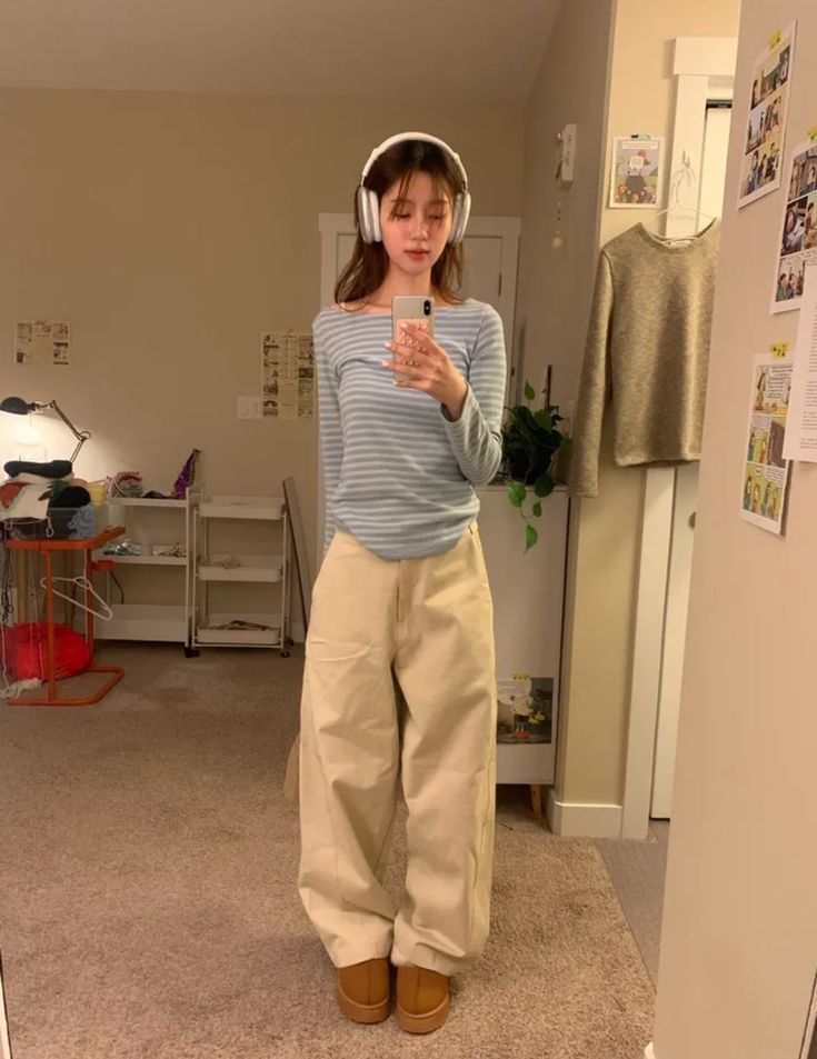 A striped long sleeve top and baggy beige pants with brown slip-on shoes.