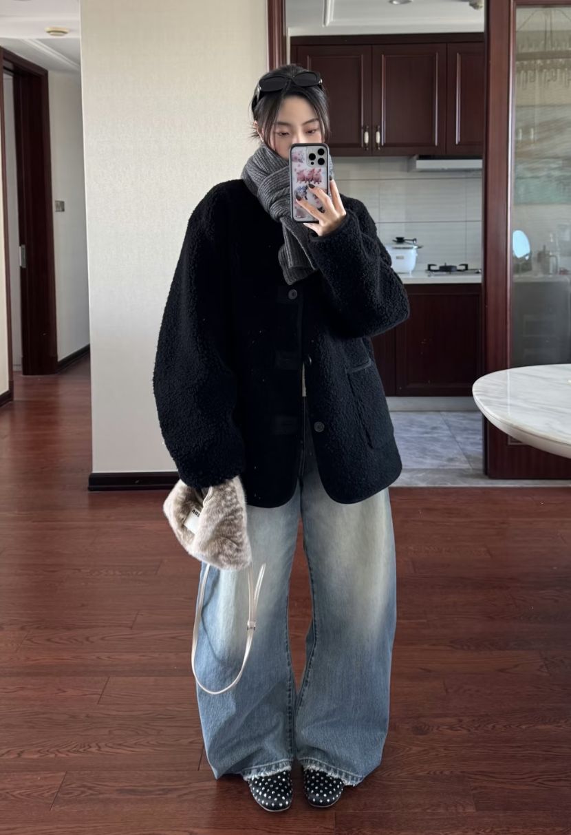 The outfit features a fuzzy black coat, a dark gray scarf, wide-leg jeans, and polka dot shoes.