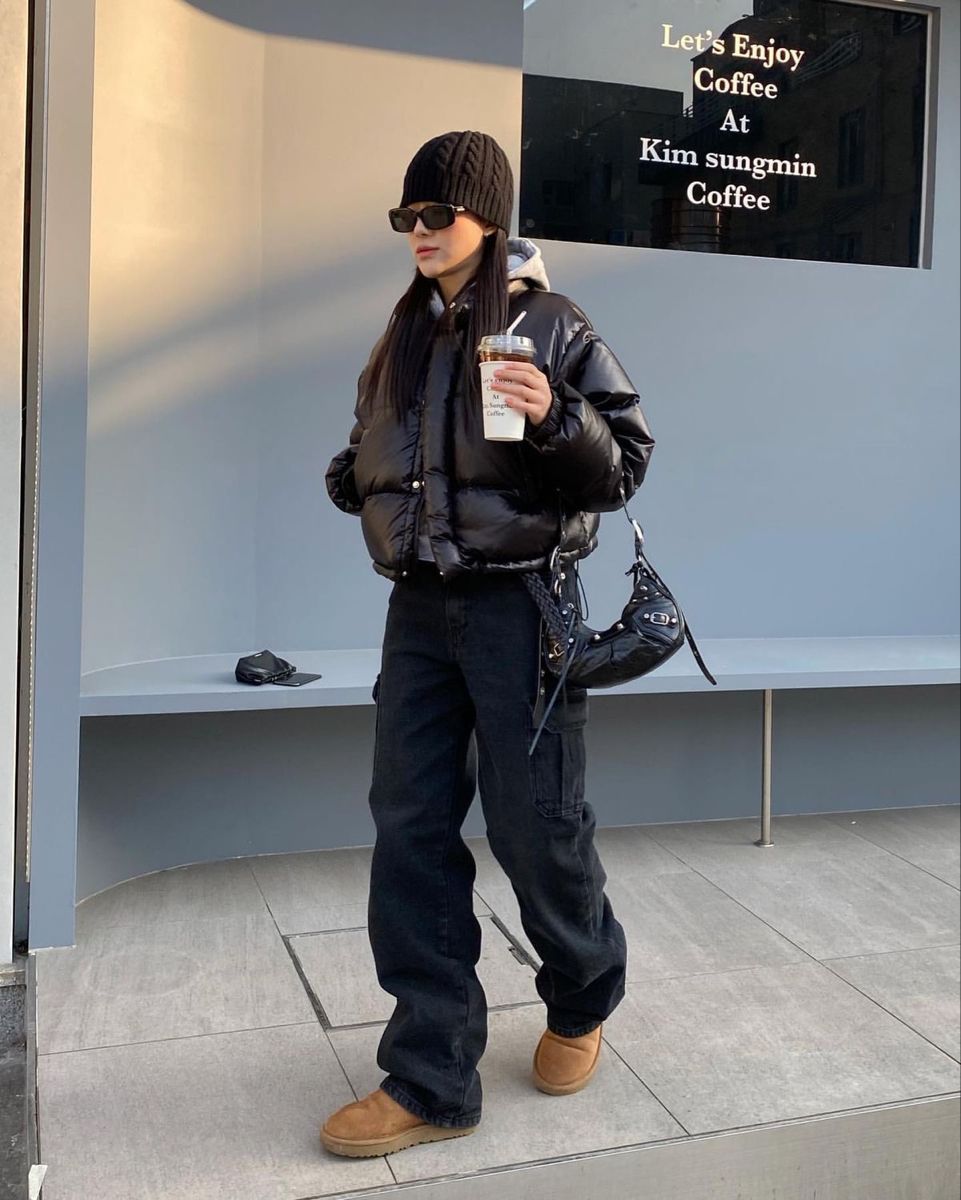 A black puffer jacket layered over a gray hoodie paired with baggy black jeans and tan boots.