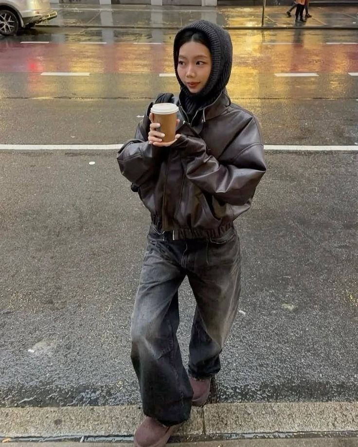 A cropped puffer jacket in dark brown with baggy jeans and a black knit hood.
