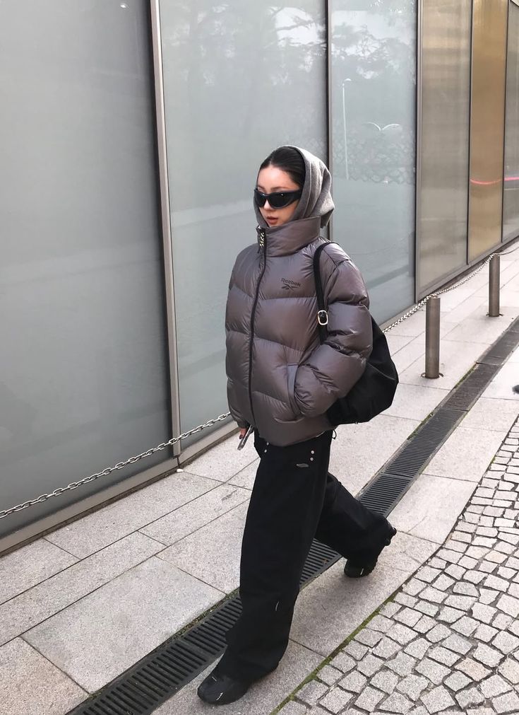 A gray puffer jacket paired with black wide leg pants and sunglasses.