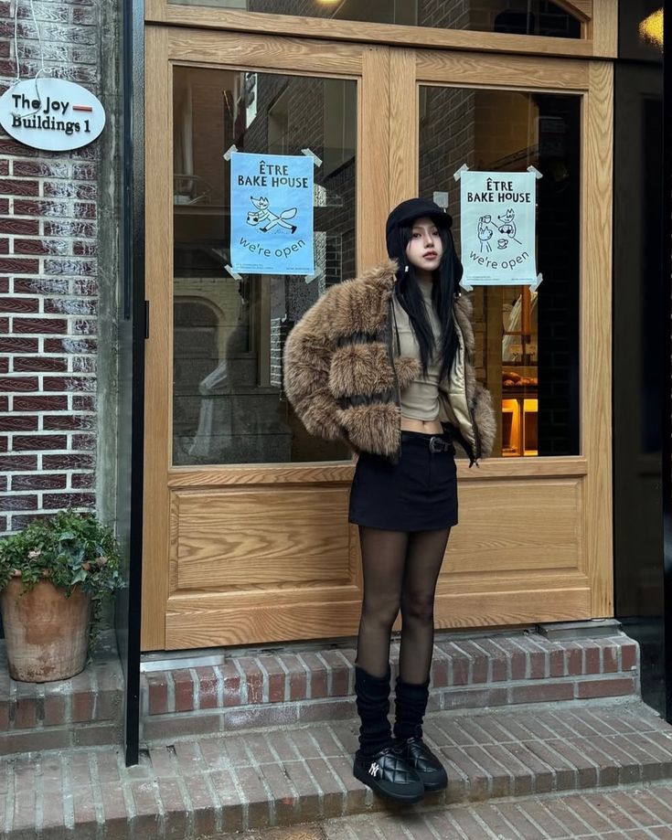 Outfit features a faux fur jacket, cropped top, mini skirt, and chunky shoes styled for winter.