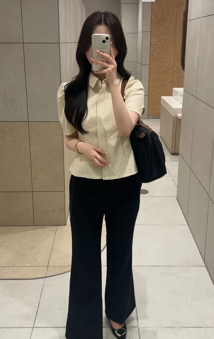A textured button-up top in light yellow paired with black flared trousers and a black handbag.