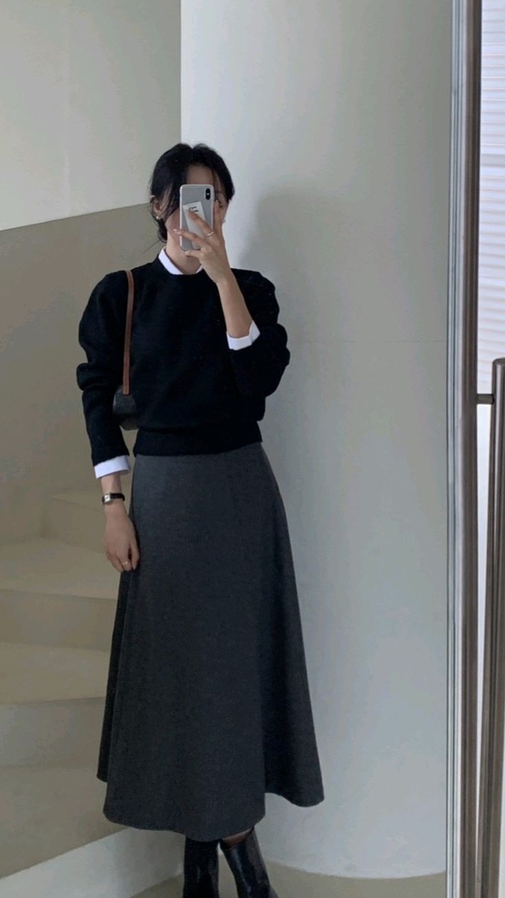 Outfit features a black sweater, a gray midi skirt, and black knee-high boots.