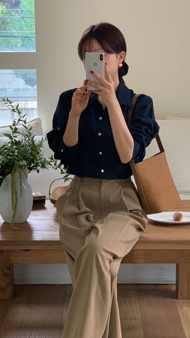 The outfit consists of a navy button-up shirt and beige wide-leg trousers.